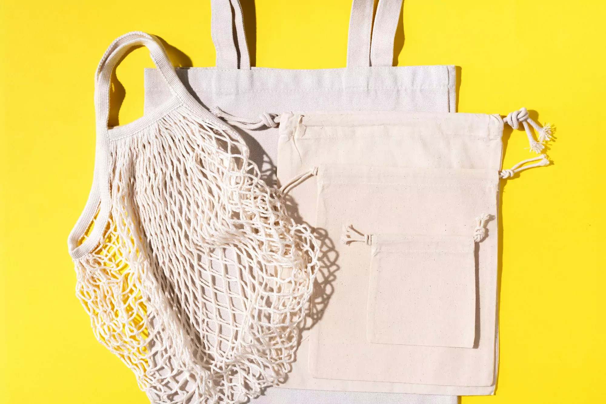 Mesh and cotton bags with on yellow background. Sustainable lifestyle. Zero waste concept. No