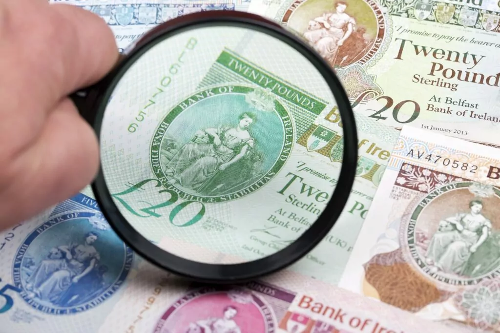 Northern Irish pounds in a magnifying glass